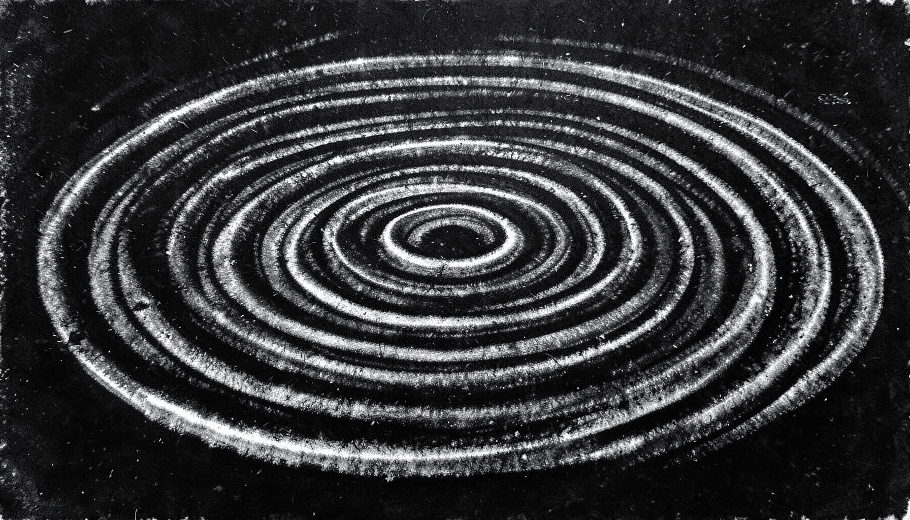 A close charcoal study of concentric ripples spreading across a dark liquid surface, with highlights catching the crest of each wave ring against a near-black background.